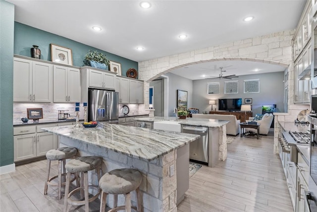 4644 Arques Ave, Round Rock, TX 78681 - kitchen featuring appliances with stainless steel finishes, an island with sink, a ceiling fan, arched walkways, and recessed lighting