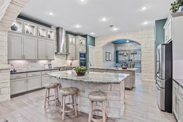 4644 Arques Ave, Round Rock, TX 78681 - kitchen featuring wall chimney exhaust hood, stainless steel appliances, an island with sink, light wood-style floors, and recessed lighting