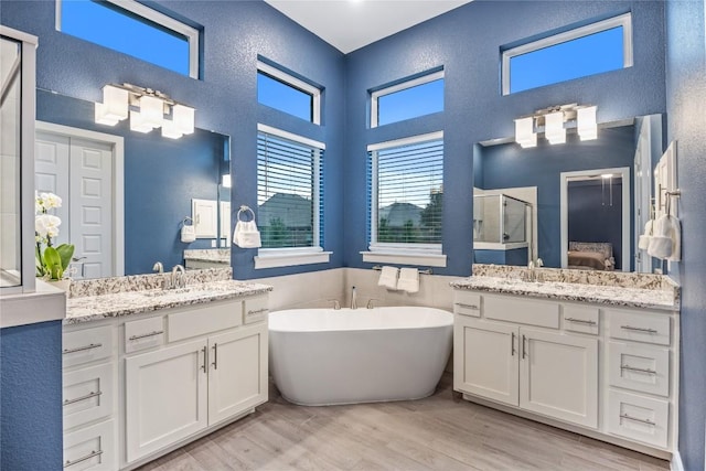 4644 Arques Ave, Round Rock, TX 78681 - full bath with a stall shower, a high ceiling, two vanities, a freestanding bath, and wood finished floors