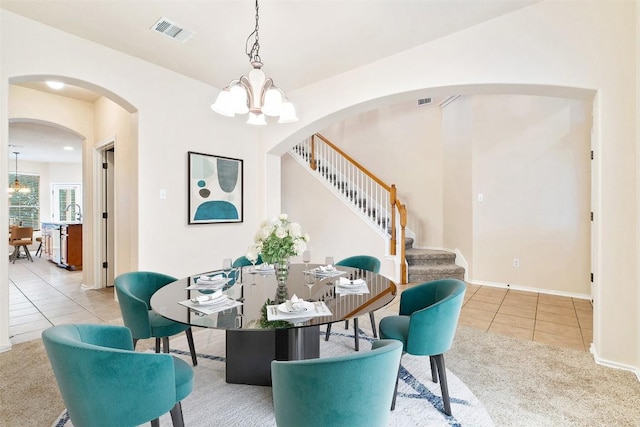 36 White Magnolia Cir, Austin, TX 78734 - carpeted dining space with tile patterned floors, stairway, arched walkways, and a chandelier