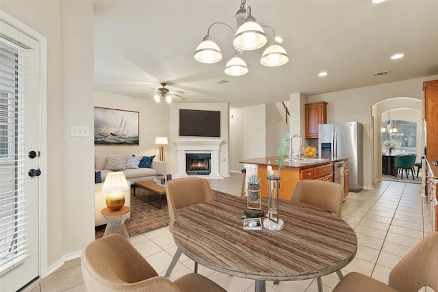 36 White Magnolia Cir, Austin, TX 78734 - dining area featuring light tile patterned floors, a ceiling fan, arched walkways, a warm lit fireplace, and recessed lighting