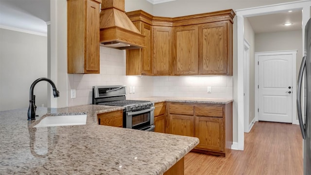 208 Rachel Loop, Burnet, TX 78611 - kitchen featuring stainless steel gas range oven, custom range hood, crown molding, decorative backsplash, and light stone counters