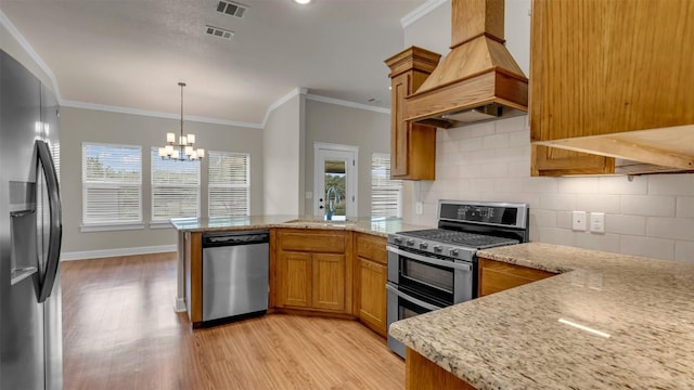208 Rachel Loop, Burnet, TX 78611 - kitchen with stainless steel appliances, custom exhaust hood, a peninsula, a chandelier, and light wood-style floors