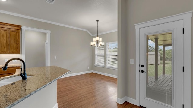 208 Rachel Loop, Burnet, TX 78611 - kitchen with wood finished floors, ornamental molding, decorative light fixtures, a chandelier, and light stone counters