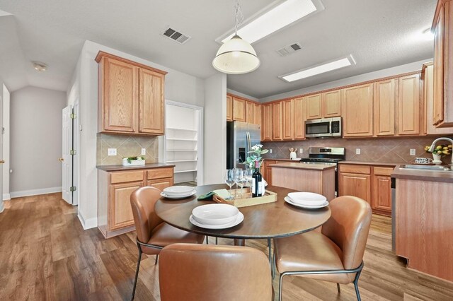10421 Beard Ave, Austin, TX 78748 - kitchen with stainless steel appliances, light wood-style flooring, backsplash, a kitchen island, and vaulted ceiling