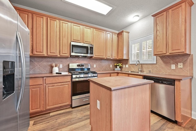 10421 Beard Ave, Austin, TX 78748 - kitchen featuring appliances with stainless steel finishes, light wood-style flooring, a center island, light countertops, and backsplash
