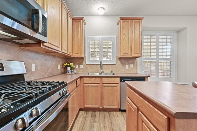 10421 Beard Ave, Austin, TX 78748 - kitchen featuring stainless steel appliances, light wood finished floors, light brown cabinetry, backsplash, and light countertops