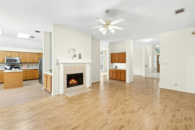 1212 Dove Cir, Cedar Park, TX 78613 - unfurnished living room with light wood-type flooring, a ceiling fan, a tile fireplace, and plenty of natural light