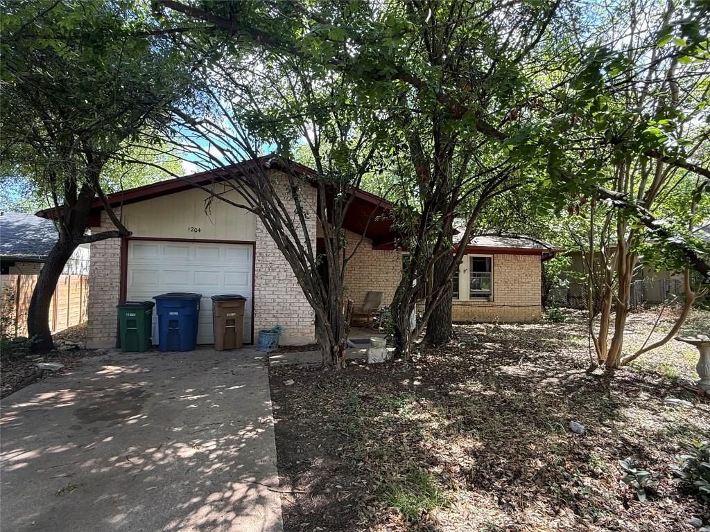 1204 Dunstan Dr, Austin, TX 78745 - view of side of home featuring brick siding, driveway, and a garage