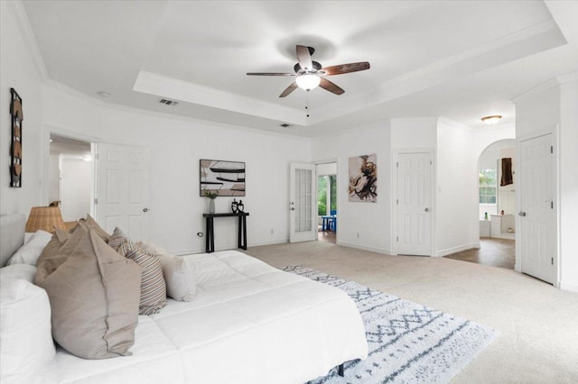 1109 Sherrill Ln, Lexington, TX 78947 - carpeted bedroom featuring a raised ceiling, crown molding, arched walkways, ensuite bath, and a ceiling fan