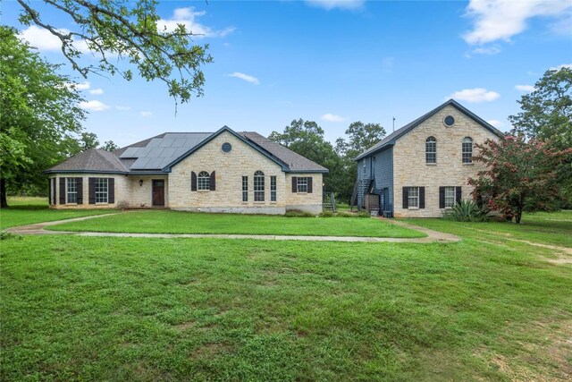 1109 Sherrill Ln, Lexington, TX 78947 - french country home with stone siding, roof mounted solar panels, and a front yard