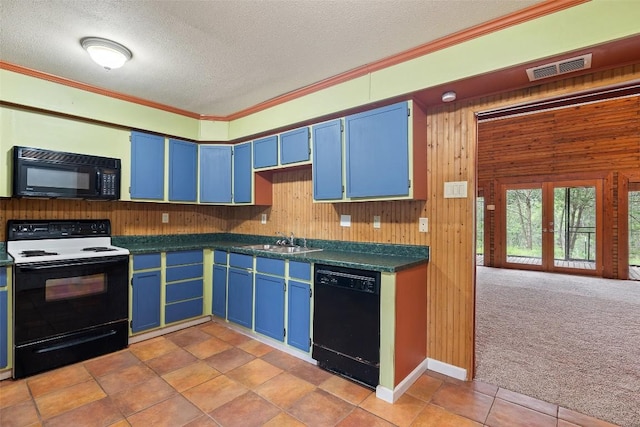 111 Sendero Blvd, Cedar Creek, TX 78612 - kitchen with black appliances, blue cabinets, dark countertops, crown molding, and wooden walls