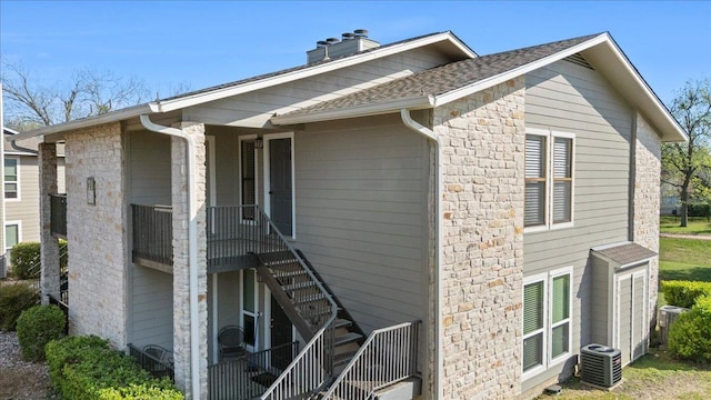 10616 Mellow Meadows Dr Unit 21C, Austin, TX 78750 - view of side of home with stone siding, a chimney, stairs, and a shingled roof