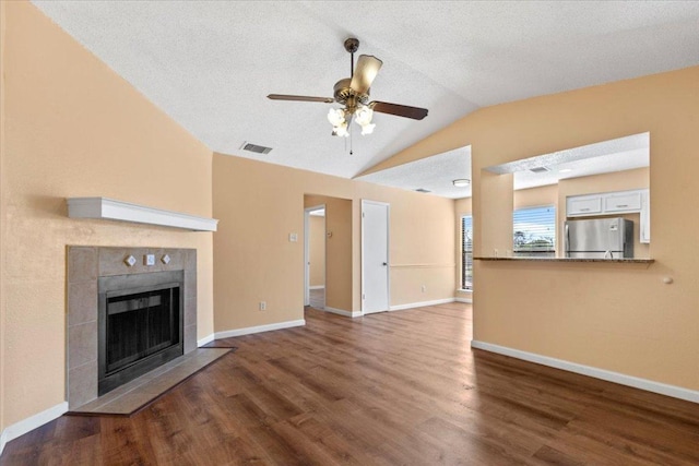 10616 Mellow Meadows Dr Unit 21C, Austin, TX 78750 - unfurnished living room featuring vaulted ceiling, ceiling fan, a tiled fireplace, and wood finished floors
