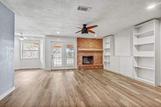 908 Hollybluff St, Austin, TX 78753 - unfurnished living room featuring ceiling fan, a textured ceiling, light wood-style floors, built in features, and a brick fireplace