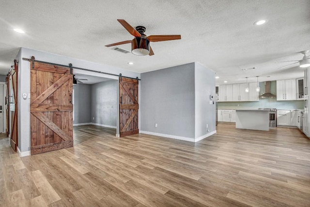 908 Hollybluff St, Austin, TX 78753 - unfurnished living room featuring a ceiling fan, a barn door, light wood-style flooring, a textured ceiling, and recessed lighting