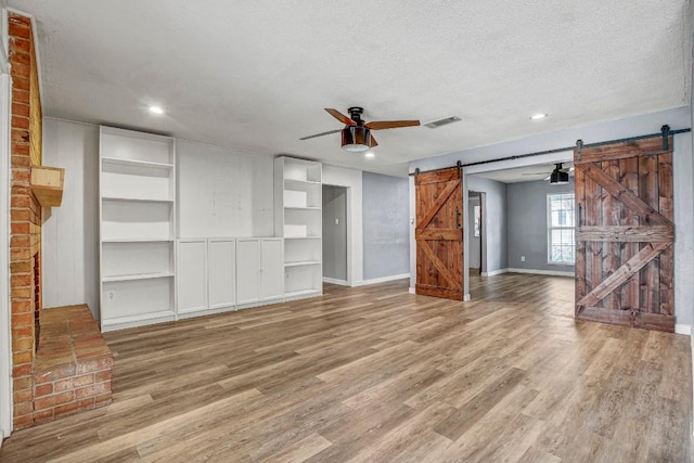 908 Hollybluff St, Austin, TX 78753 - unfurnished living room with a barn door, ceiling fan, wood finished floors, a textured ceiling, and recessed lighting