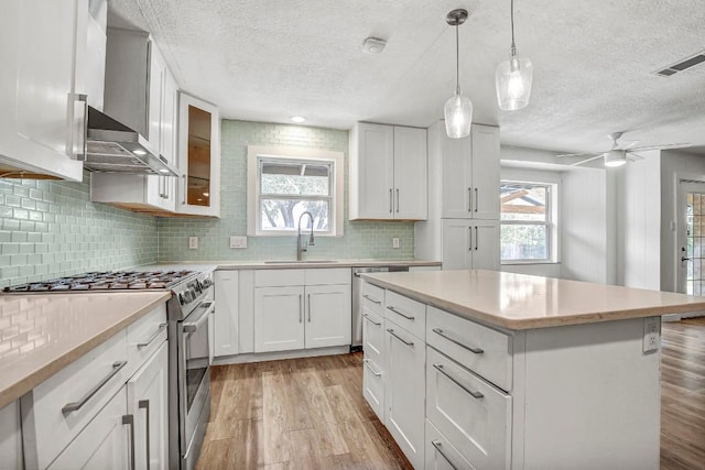 908 Hollybluff St, Austin, TX 78753 - kitchen with stainless steel appliances, a textured ceiling, light wood finished floors, wall chimney range hood, and decorative backsplash