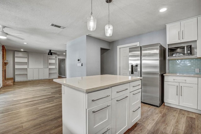 908 Hollybluff St, Austin, TX 78753 - kitchen featuring stainless steel appliances, ceiling fan, light wood-style floors, a textured ceiling, and decorative backsplash