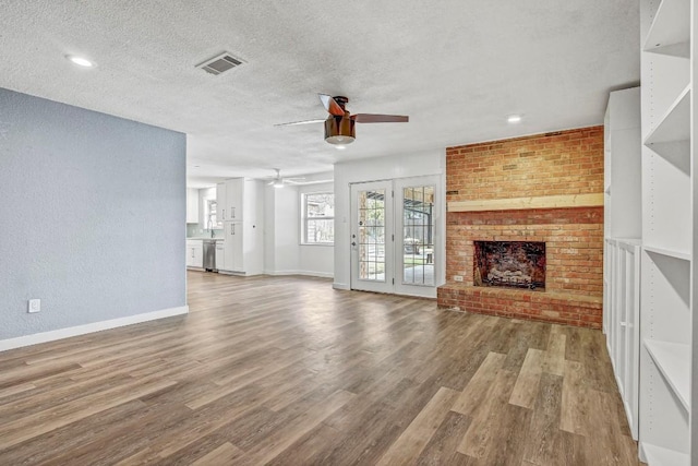 908 Hollybluff St, Austin, TX 78753 - unfurnished living room with a ceiling fan, wood finished floors, a brick fireplace, a textured ceiling, and recessed lighting