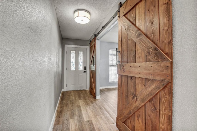908 Hollybluff St, Austin, TX 78753 - doorway to outside with a barn door, a textured wall, light wood-type flooring, and a textured ceiling