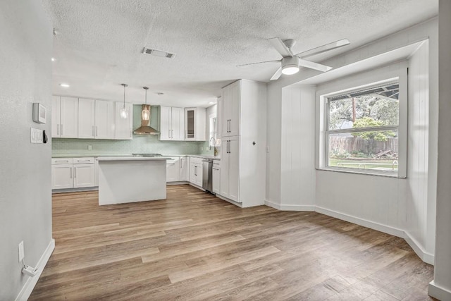 908 Hollybluff St, Austin, TX 78753 - kitchen with wall chimney exhaust hood, appliances with stainless steel finishes, light countertops, a textured ceiling, and white cabinetry