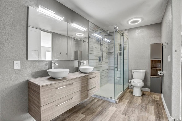 908 Hollybluff St, Austin, TX 78753 - bathroom featuring a textured wall, double vanity, wood finished floors, and a stall shower