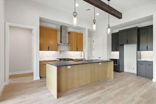 512 Cowal Dr S, Spicewood, TX 78669 - kitchen featuring wall chimney exhaust hood, decorative backsplash, light wood finished floors, beamed ceiling, and dark countertops