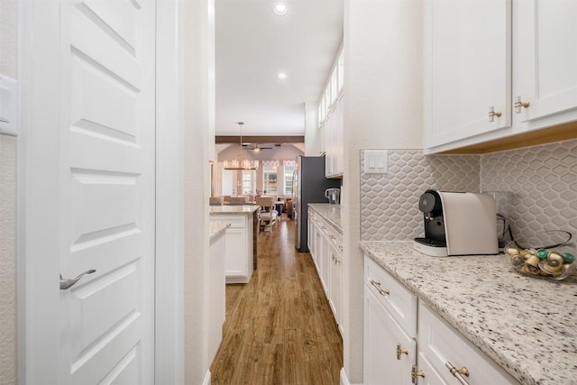 6708 Leonardo Dr, Round Rock, TX 78665 - kitchen with light wood-style flooring, white cabinetry, backsplash, light stone countertops, and recessed lighting
