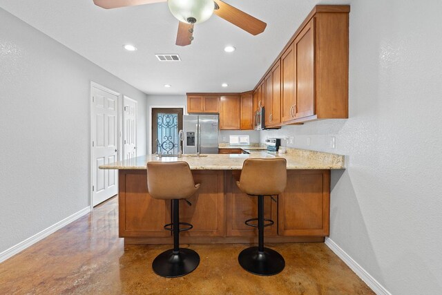 5700 Jain Ln, Austin, TX 78721 - kitchen with concrete flooring, brown cabinetry, a peninsula, light stone countertops, and stainless steel refrigerator with ice dispenser