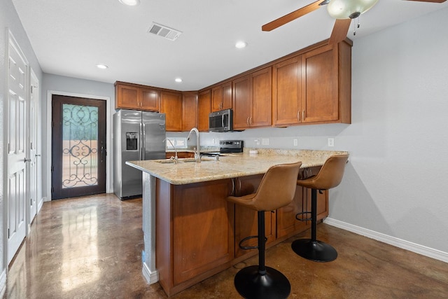 5700 Jain Ln, Austin, TX 78721 - kitchen featuring concrete floors, brown cabinetry, appliances with stainless steel finishes, a peninsula, and recessed lighting