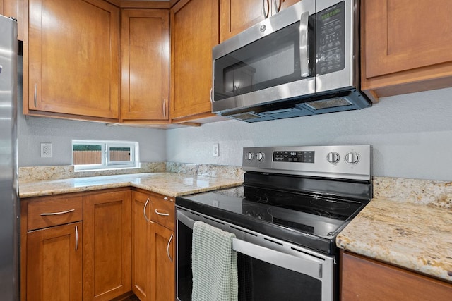 5700 Jain Ln, Austin, TX 78721 - kitchen featuring stainless steel appliances, brown cabinetry, and light stone countertops