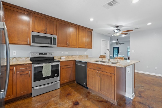 5700 Jain Ln, Austin, TX 78721 - kitchen featuring a peninsula, stainless steel appliances, brown cabinetry, and recessed lighting