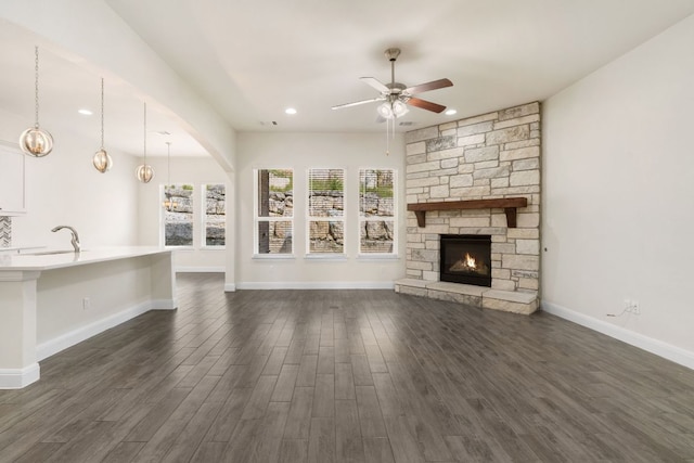 2304 Arroyo Grande, Leander, TX 78641 - unfurnished living room with a ceiling fan, dark wood-style floors, a fireplace, arched walkways, and recessed lighting