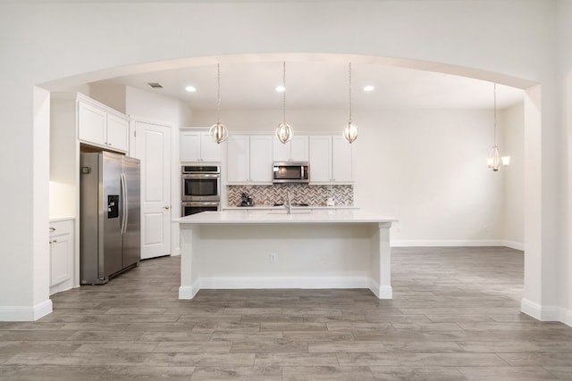 2304 Arroyo Grande, Leander, TX 78641 - kitchen featuring appliances with stainless steel finishes, light countertops, tasteful backsplash, white cabinetry, and a center island with sink