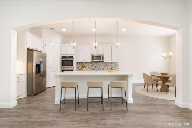 2304 Arroyo Grande, Leander, TX 78641 - kitchen featuring appliances with stainless steel finishes, light countertops, white cabinets, backsplash, and light wood-type flooring