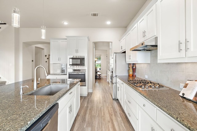 1304 Positano Pass, Leander, TX 78641 - kitchen featuring appliances with stainless steel finishes, under cabinet range hood, arched walkways, light wood finished floors, and recessed lighting