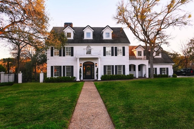 4119 Hidden Canyon Cv, Austin, TX 78746 - colonial-style house with a front yard, a balcony, a chimney, and brick siding