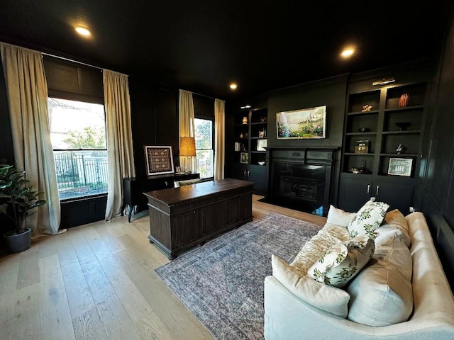 4119 Hidden Canyon Cv, Austin, TX 78746 - home office featuring a fireplace with flush hearth, light wood-type flooring, and built in shelves