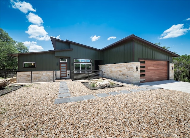 3013 Clark Ave, Lago Vista, TX 78645 - contemporary house with stone siding, driveway, an attached garage, and board and batten siding