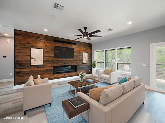 3013 Clark Ave, Lago Vista, TX 78645 - living room with light wood-style flooring, recessed lighting, a ceiling fan, wood walls, and a glass covered fireplace