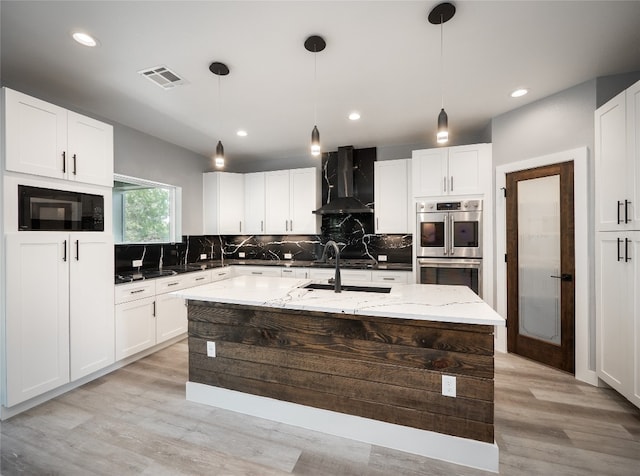 3013 Clark Ave, Lago Vista, TX 78645 - kitchen featuring wall chimney exhaust hood, appliances with stainless steel finishes, tasteful backsplash, light stone counters, and light wood-style floors
