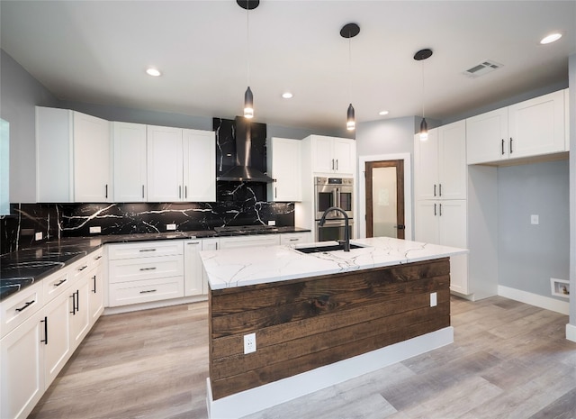3013 Clark Ave, Lago Vista, TX 78645 - kitchen featuring wall chimney range hood, backsplash, light wood finished floors, light stone countertops, and white cabinets