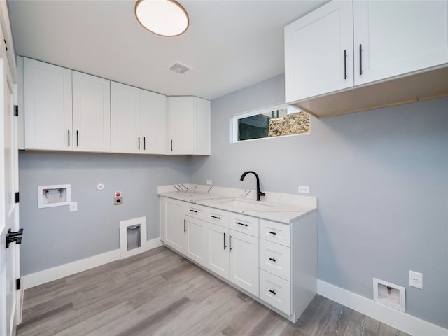 3013 Clark Ave, Lago Vista, TX 78645 - laundry room featuring electric dryer hookup, cabinet space, hookup for a gas dryer, light wood-type flooring, and hookup for a washing machine