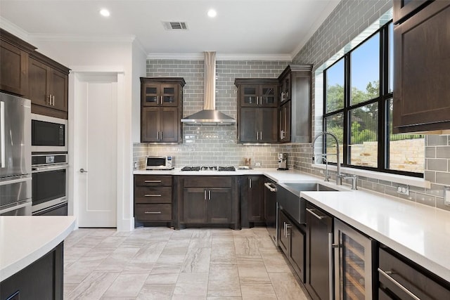 209 Ringtail Stream Dr, Lakeway, TX 78738 - kitchen featuring appliances with stainless steel finishes, wall chimney exhaust hood, ornamental molding, wine cooler, and light countertops
