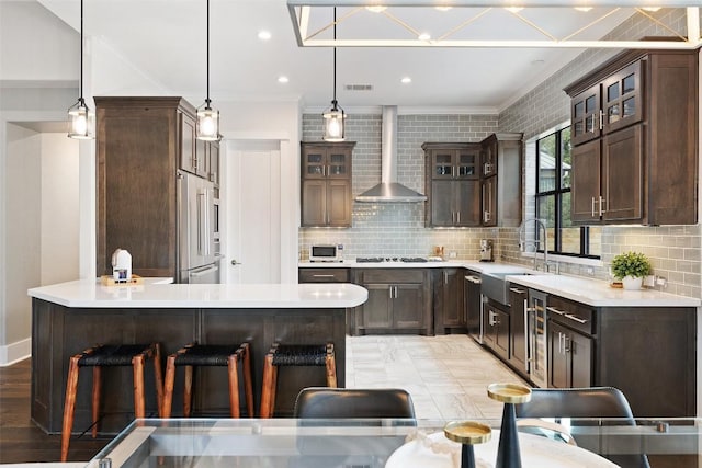 209 Ringtail Stream Dr, Lakeway, TX 78738 - kitchen with wall chimney exhaust hood, crown molding, dark brown cabinets, a kitchen bar, and backsplash
