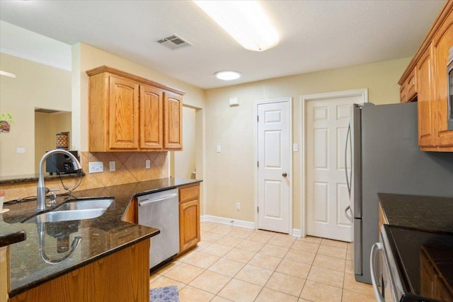 2802 Amber Forest Trl, Belton, TX 76513 - kitchen featuring stainless steel dishwasher, backsplash, dark stone counters, light tile patterned floors, and a peninsula