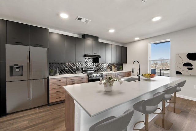 4510 Terry-O Ln Unit 322, Austin, TX 78745 - kitchen featuring stainless steel appliances, a breakfast bar area, dark wood-style flooring, tasteful backsplash, and extractor fan