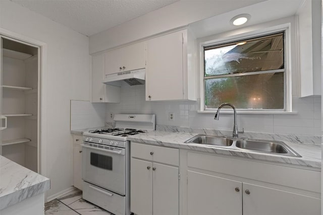 2616 Audubon Pl, Austin, TX 78741 - kitchen featuring white gas range oven, under cabinet range hood, light marble finish flooring, white cabinets, and backsplash