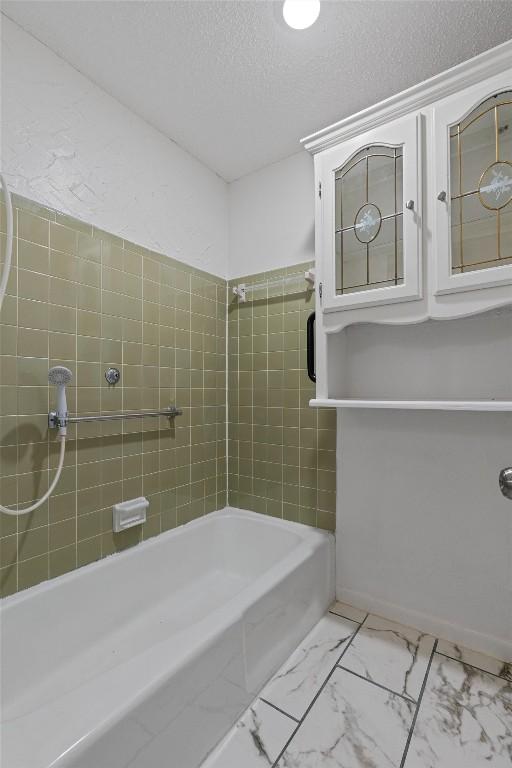 2616 Audubon Pl, Austin, TX 78741 - full bath with marble finish floors, a textured ceiling, and shower / bath combination